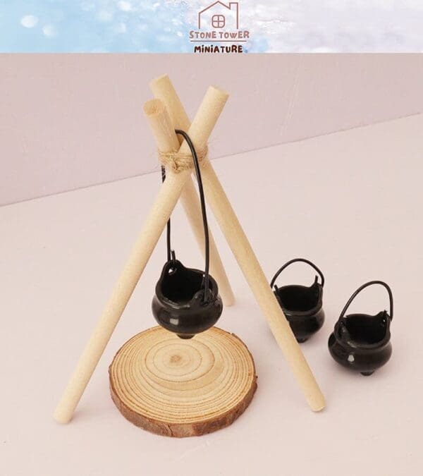 Miniature black pots and wooden tripod displayed on a wood slice base, with a "Stone Tower Miniature" label above.