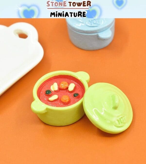 Miniature lime green pot with colorful stew, lid off, displayed on orange background with blue pot and cutting board nearby.