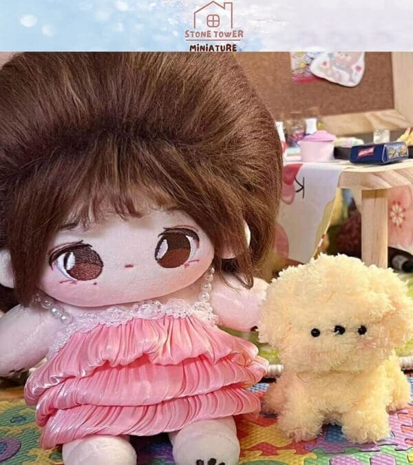 Plush doll in a pink dress sits next to a fluffy yellow toy on a colorful mat.