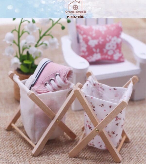 Miniature laundry baskets with pink shoes; white flowers and a pink floral pillow in the background.