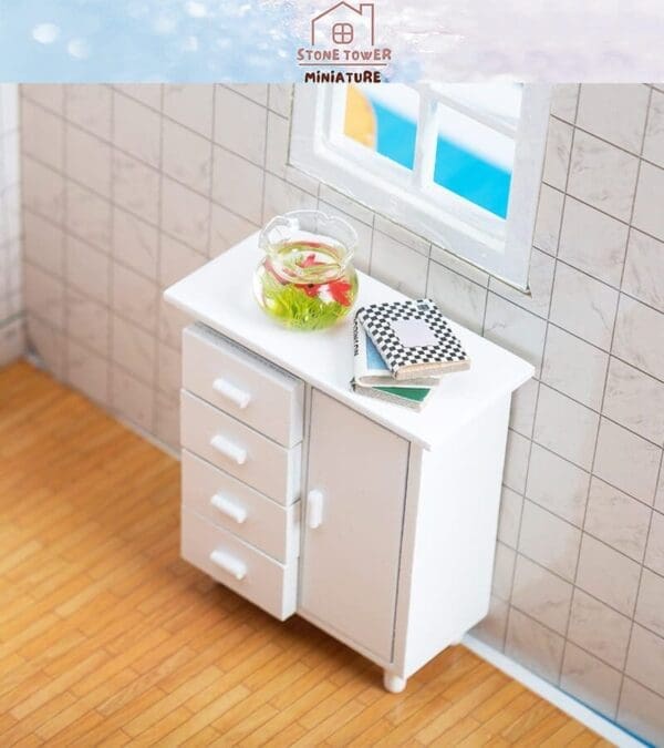 Miniature room with a white dresser, fishbowl, and books by a window.