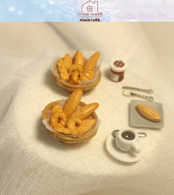 Miniature bread baskets, jam jar, and coffee cup on a white cloth background.