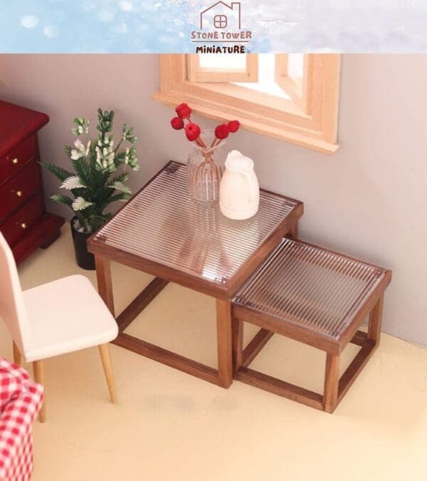 Miniature room with a wooden table, matching bench, white chair, red flowers in a vase, and a small jug.