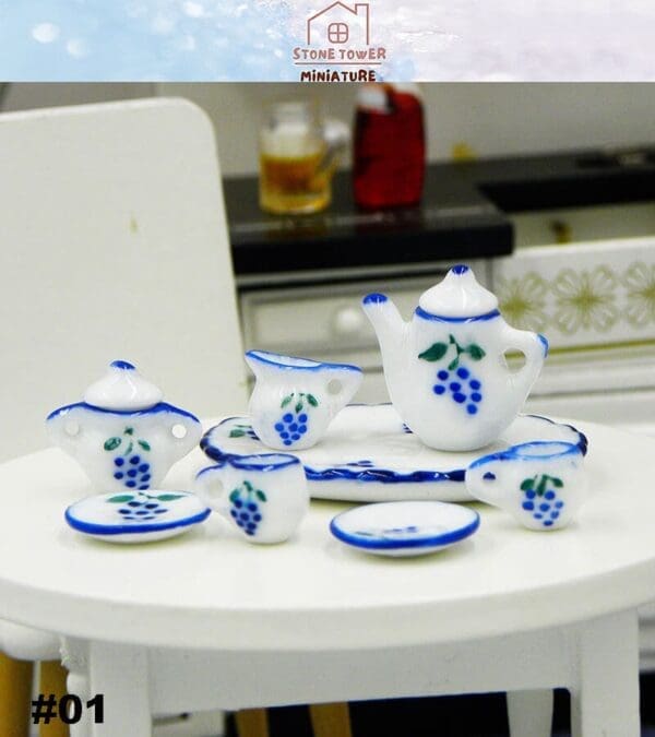 Miniature tea set with blue grape designs on a white table.