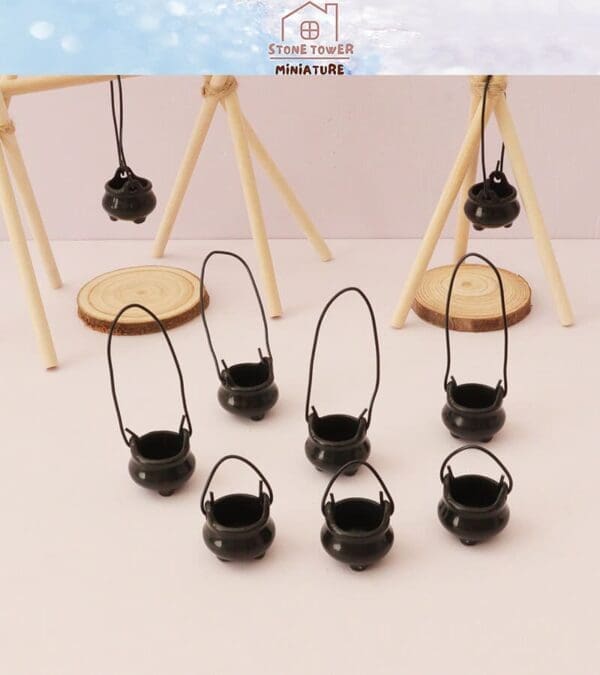 Miniature black cauldrons with handles on wooden tripods and discs, displayed on a beige surface.