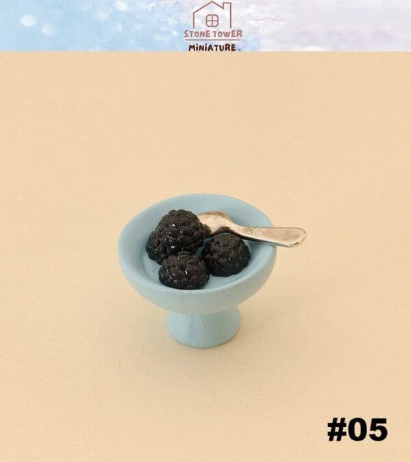 Miniature blackberries in a blue dish with a tiny silver spoon.